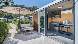 A modern outdoor kitchen area with a dining set and a large umbrella. - Apple House (Choeng Thale)