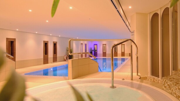 A modern indoor swimming pool with a glass wall, a hot tub, and a staircase leading to a second level. - Vacation apartment Watt`n Blick 220: Comfortable vacation right on the beach in Cuxhaven (Cuxhaven)