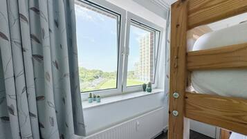 A room with a window overlooking a parking lot and buildings, a radiator, and a wooden door.