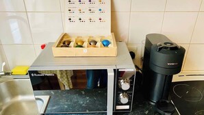 A kitchen with a Russell Hobbs microwave, a Nespresso coffee machine, and a drawer with various kitchen utensils. - London Style (5) Apartment (Greater London)