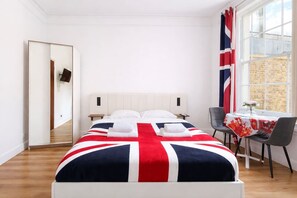 Ein Hotelzimmer mit einem Bett, einem Sessel, einem Tisch mit Tischdecke und einem Fenster mit Vorhängen.