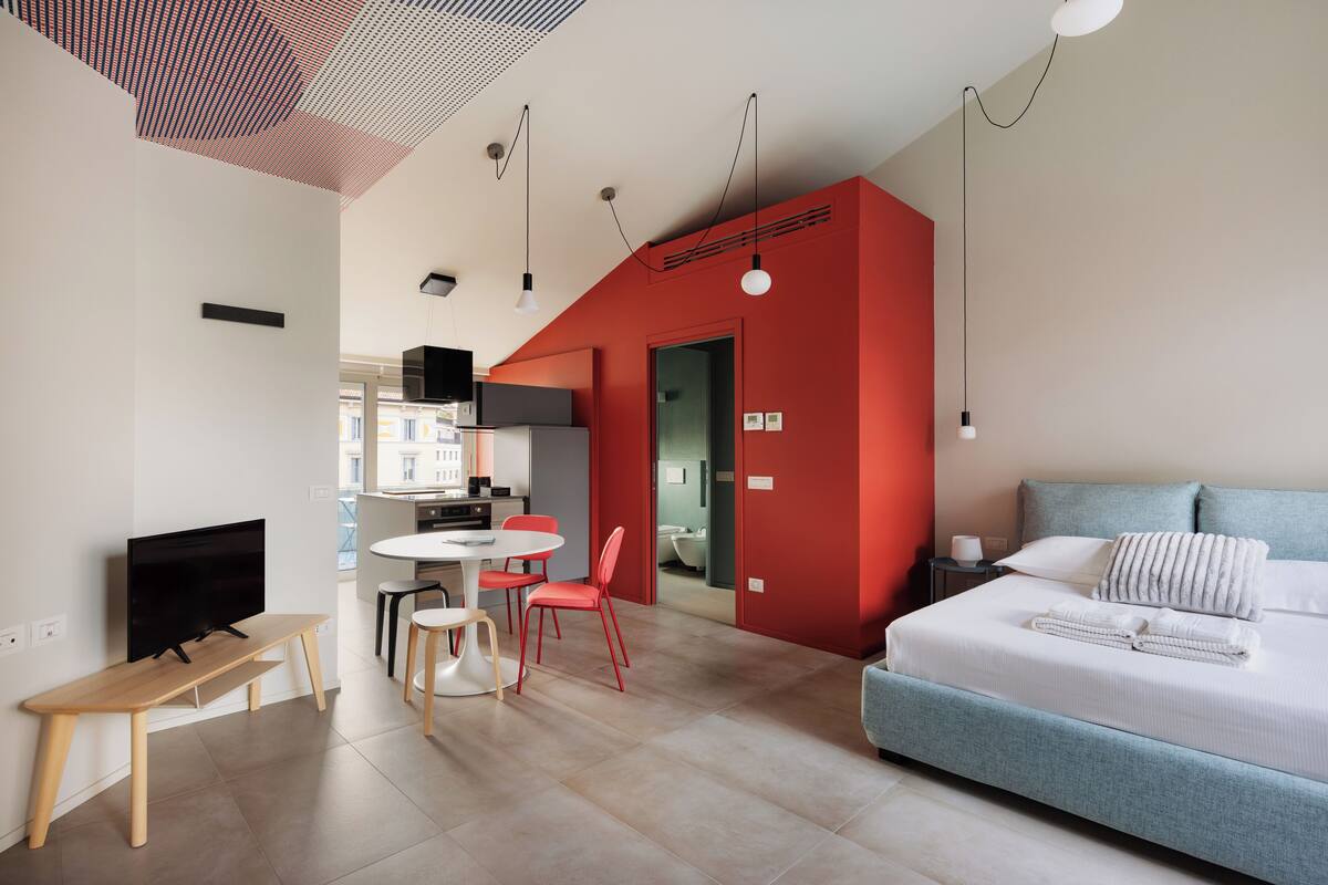 Une chambre d’hôtel moderne équipée d’un lit, d’une télévision, d’un coin repas avec des chaises et d’un coin cuisine.
