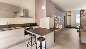 A modern kitchen with a central island, bar stools, and a built-in oven. - DONIZETTI STUDIOS (Bergamo)