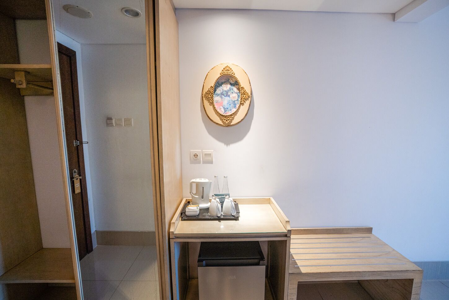 A hotel room with a wooden desk, a coffee maker, and a trash bin.