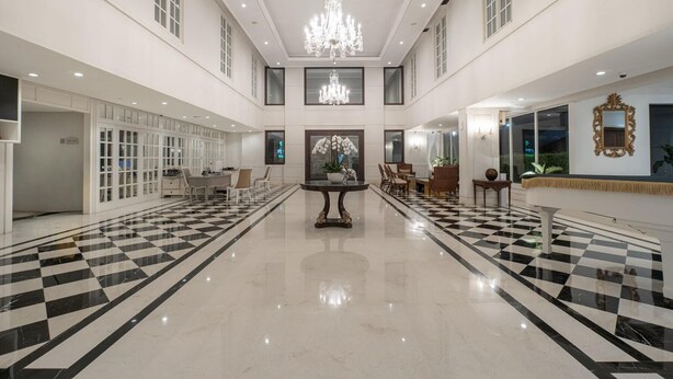 A spacious lobby with a checkered floor, a central chandelier, and a seating area with tables and chairs. - NIMS Hotel Seminyak (Seminyak)