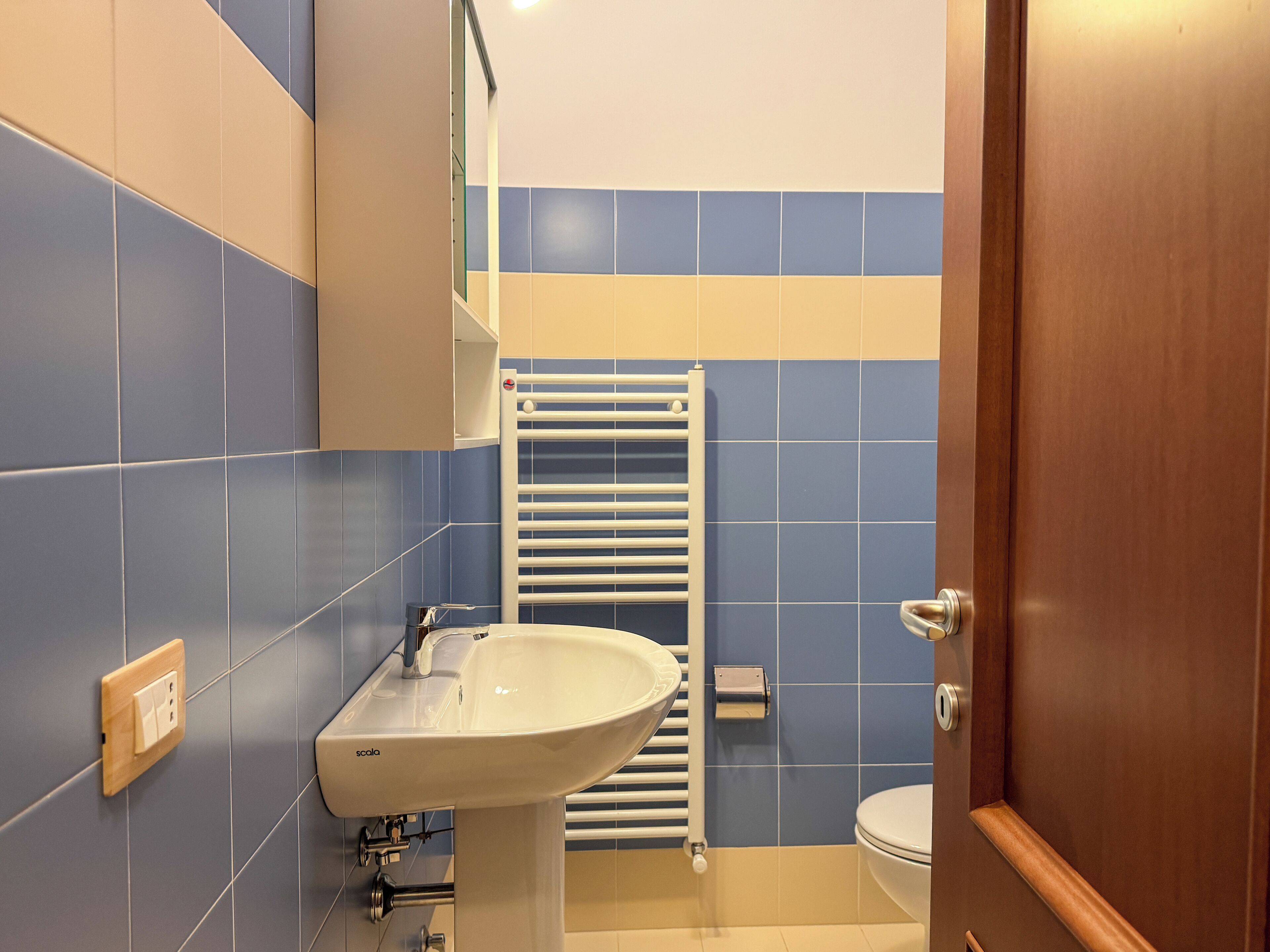 A bathroom with a white sink, a towel rack, and a toilet.