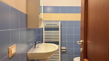 A bathroom with a white sink, a towel rack, and a toilet.
