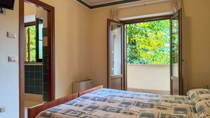 A bedroom with a bed, a window, and a door leading to a balcony. - Hotel Fanesia Coliving (Fano Adriano)