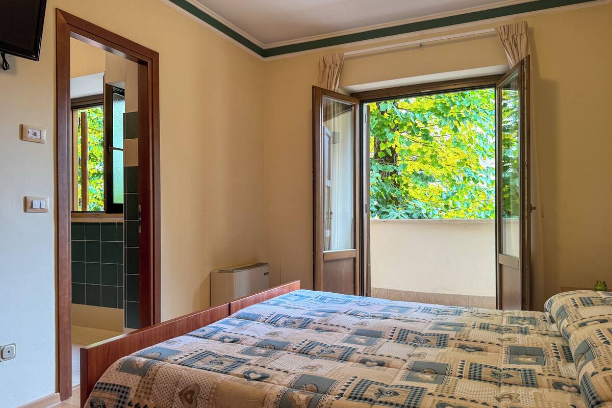 Ein Schlafzimmer mit Bett, Fenster und einer Tür, die auf einen Balkon führt.
