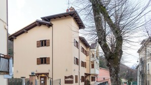 A multi-story building with a beige facade, brown shutters, and a stone-paved entrance. - Hotel Fanesia Coliving (Fano Adriano)
