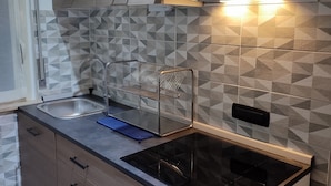 A modern kitchen with a built-in stove, a sink, and a metal drying rack.