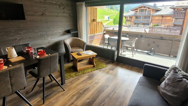 Un intérieur moderne comprenant un coin repas, un canapé et de grandes fenêtres donnant sur une station de ski.