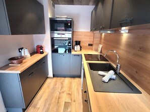 Eine kompakte Küche mit Backofen, Kaffeemaschine und Spüle mit Handtuch.