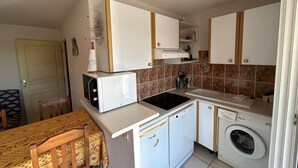 Een kleine keuken met een magnetron, vaatwasser en wasmachine.