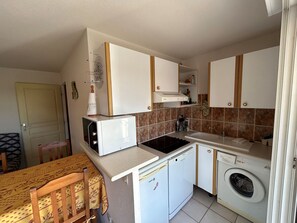 A compact kitchen with a microwave, dishwasher, and washing machine.
