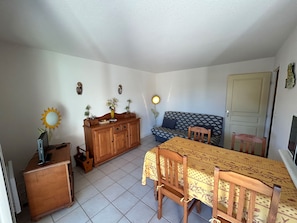A room with a dining table, chairs, a sofa, a wooden cabinet, and a door.