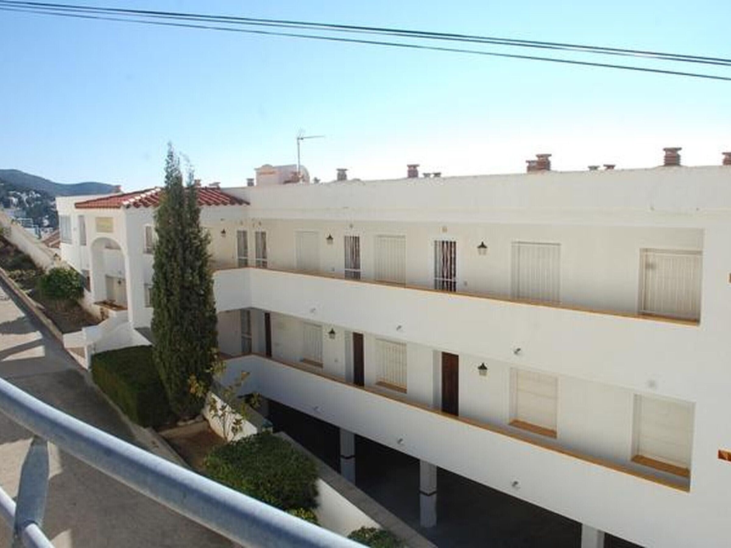 A multi-story residential building with balconies, a central courtyard, and a clear view of the surrounding neighborhood.