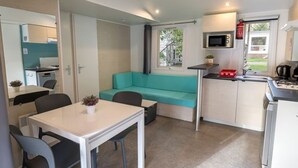 A compact kitchen with a dining area, a teal sofa, and a small table with chairs.