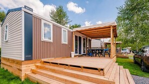 A mobile home with a wooden deck and a covered patio area.