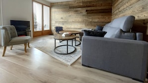Ein modernes Wohnzimmer mit einem grauen Sofa, einem runden Couchtisch und einem Fernseher auf einem Lowboard.