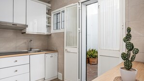 A modern kitchen with white cabinets, a stainless steel range hood, and a wooden countertop.