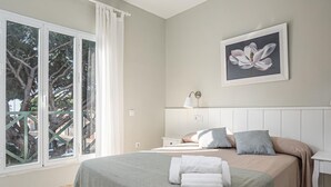 A bedroom with a bed, a nightstand, a lamp, and a window with curtains.
