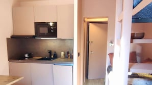 A compact kitchen with a microwave, sink, and cabinets. There's a small table and a door leading to a bedroom with a bunk bed. - Modern and cozy studio at the foot of the slopes in Isola 2000 (Isola 2000)