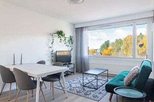 Una sala de estar moderna con comedor, televisión y vistas a árboles otoñales.