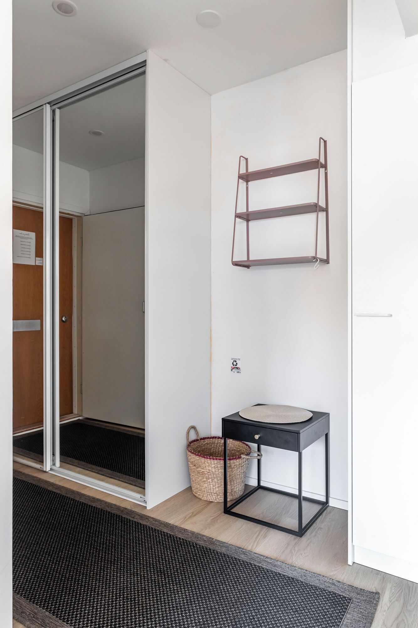A modern bathroom with a glass shower door, a sink with a black frame, and a metal shelf on the wall.