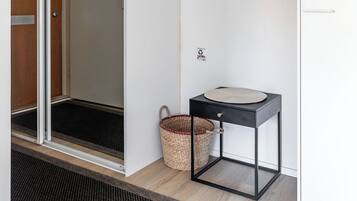 A modern bathroom with a glass shower door, a sink with a black frame, and a metal shelf on the wall.