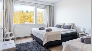 A bedroom with a large window, a bed with pillows and a blanket, a bedside table, and a chair. - 1BR Apartments next to Railway Station, Free Parking, Balcony (Lahti)