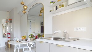 A modern kitchen with white cabinetry, a stainless steel sink, and a built-in oven. There is a dining area with white chairs and a round table. - TraStella: Classy Rome Stay close to Trastevere St, (Roma)