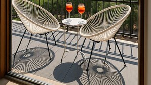 A balcony with two wicker chairs and a small table, two glasses of red drink, and a view of buildings and trees. - TraStella: Classy Rome Stay close to Trastevere St, (Roma)