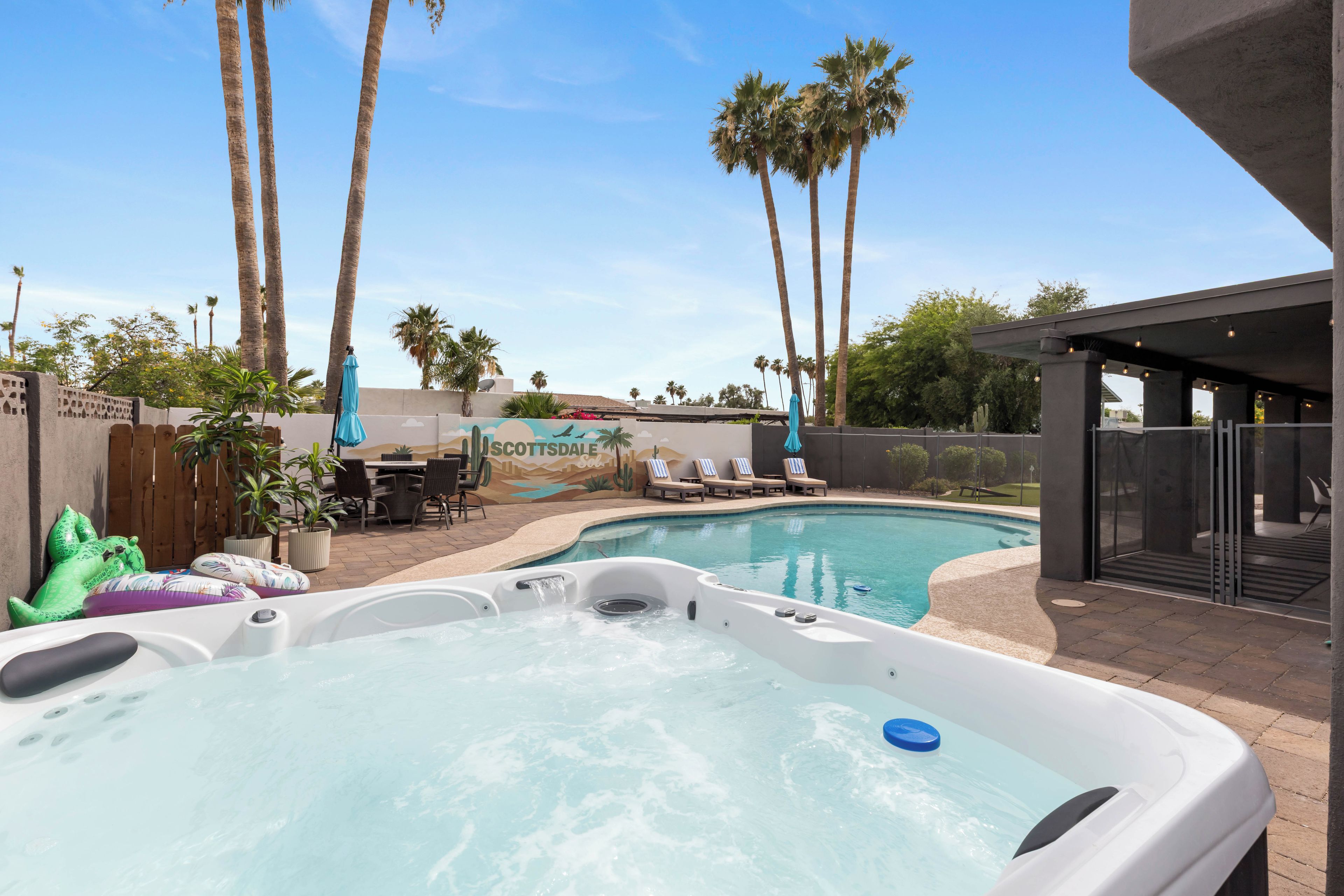 A swimming pool with hot tubs, palm trees, and a covered patio area.