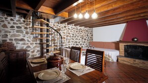 A dining area with a stone wall, wooden staircase, and a fireplace. - To spiti sto castro (Nafpaktos)