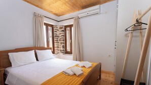 A bedroom with a wooden bed, a stone wall, and a wooden ceiling. - To spiti sto castro (Nafpaktos)