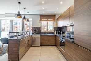 A modern kitchen with wooden cabinets, a built-in dishwasher, and pendant lighting.