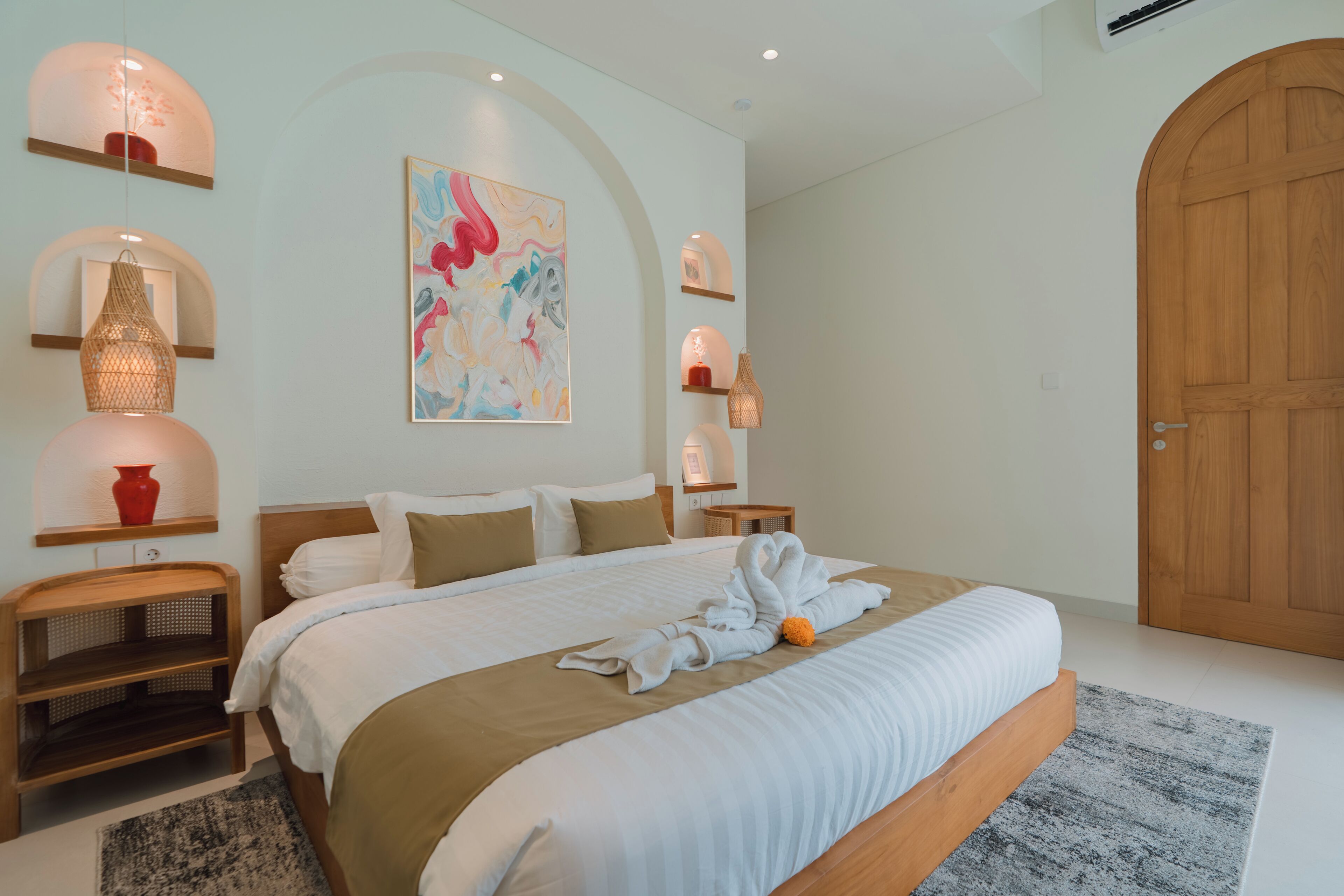Une chambre d’hôtel moderne avec un grand lit, une porte en bois et un tableau au mur.