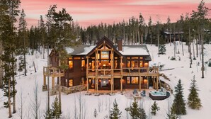 A large wooden lodge with multiple levels, surrounded by snow and trees.