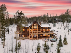 A large wooden lodge with multiple levels, surrounded by snow and trees.