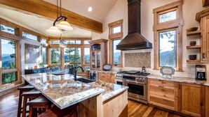 A spacious kitchen with a large island, wooden cabinets, and a view of the mountains.