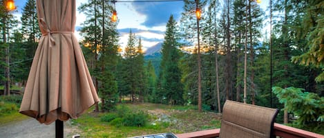 An outdoor seating area with a view of a forest and mountains.
