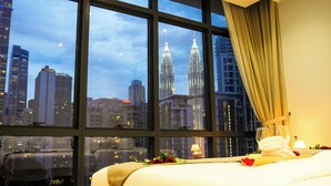 Une chambre d’hôtel dotée d’une grande fenêtre donnant sur les tours Petronas.