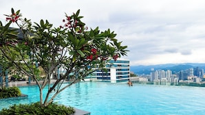 Une piscine offrant une vue sur le paysage urbain, entourée de verdure et de bâtiments modernes.