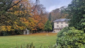 A two-story house with a balcony, surrounded by a well-maintained lawn and trees with autumn foliage. - Lovelady Shield House (Alston)