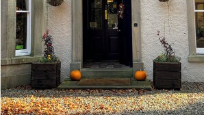 A building with a symmetrical facade, a central entrance with a pediment, and two potted plants on either side of the door. - Lovelady Shield House (Alston)