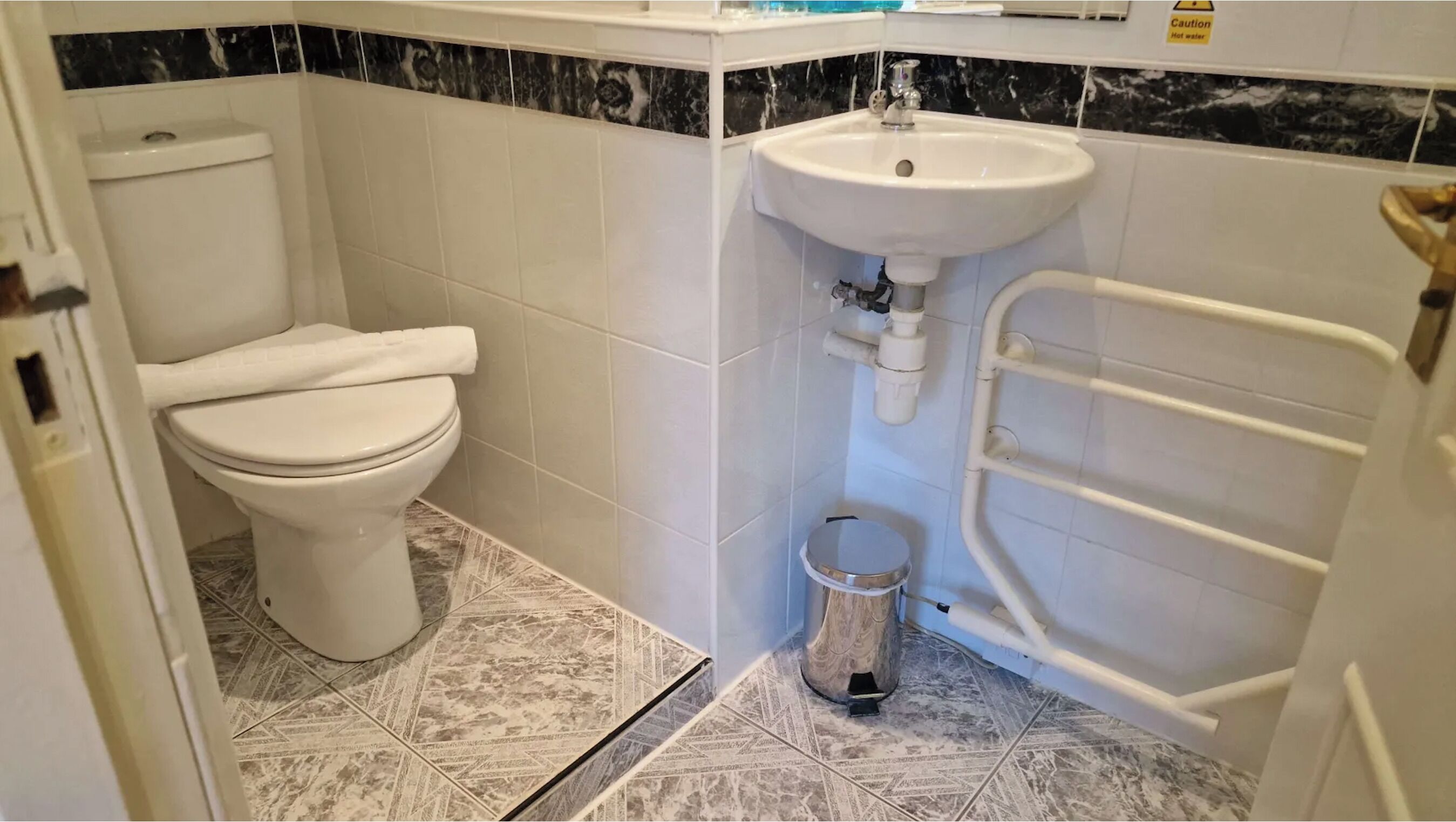 Un baño pequeño con inodoro, lavamanos y barandilla.