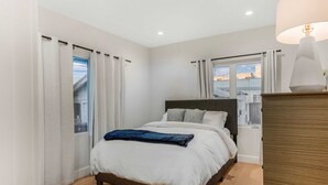 A bedroom with a bed, curtains, a window, and a lamp. - Pet Friendly, Modern, Mins to Retro Row & Beach (Long Beach)