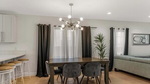 A modern kitchen with a dining table, bar stools, and a chandelier. - Pet Friendly, Modern, Mins to Retro Row & Beach (Long Beach)