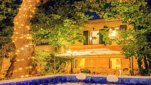 A nighttime view of a house with a swimming pool, surrounded by trees and illuminated by string lights. - Leonardo House Pisa Garden Center Whirlpool Pool (Pisa)